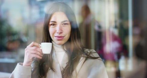 One morning a beautiful elegant woman eats breakfast at the outdoor bar with a coffee and croissan
