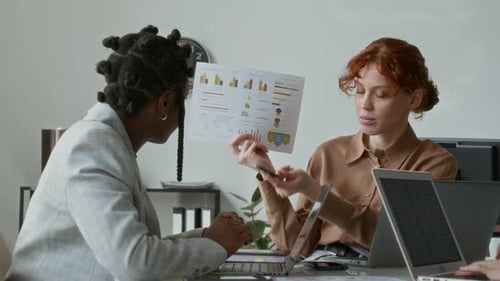 Women Discuss Charts in a Corporate Office
