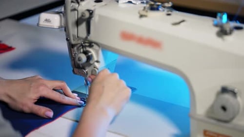 Woman works at sewing machine.