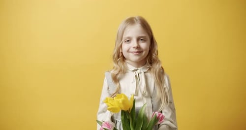 Smiling Girl with Tulips on Yellow Background