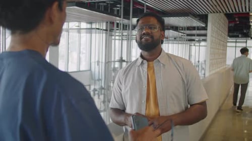 Man Having Conversation with Colleague in Office Corridor