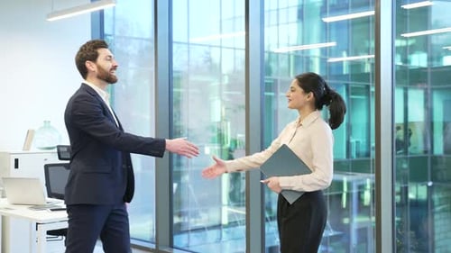 Two business people a man and a woman shaking hands after deal in a modern business office. Male