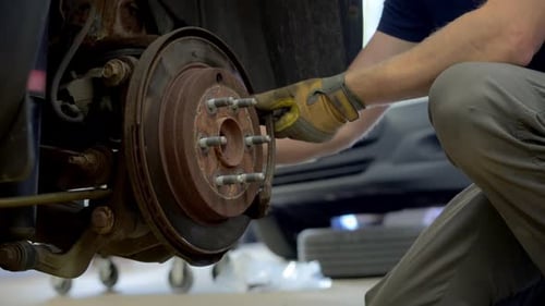 Mechanic Removing Old Brakes to Install New Ones Wheel Hub on the Car Various Devices in a Repair