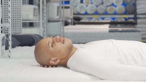 Joyful African Man Testing Orthopedic Mattress in a Stylish Furniture Store