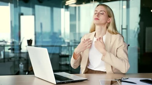 A young businesswoman is hot sitting at the workplace at the desk in a modern office.