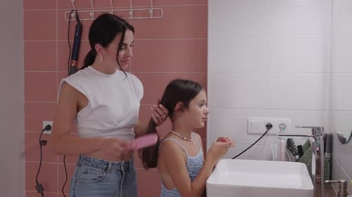 Woman Brushes Child's Hair in Bathroom