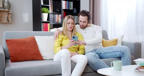 Affectionate Couple Relaxing on Sofa with Smartphone