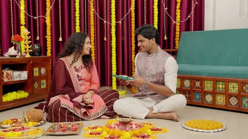 Woman Hands Man Present at Festive Gathering