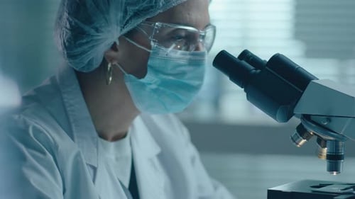 Adult Scientist Examining Sample Under Microscope in Lab