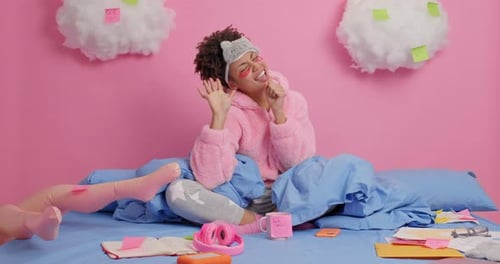 Fröhliche Afroamerikanerin tanzt und singt mit verbundenen Augen in ihrem Schlafzimmer zu Hause