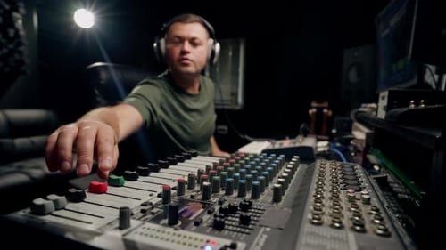 A close-up of a mixing console device used by a man working as professional sound engineer in studio