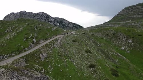 Ein grünes Tal, umgeben von wunderschönen Bergen und einer Bergstraße, die durch das Tal führt.