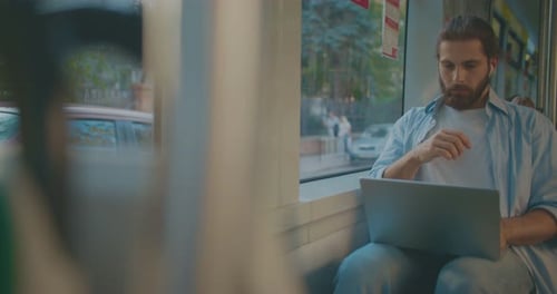 Männlicher Freelancer schreibt und liest nachdenklich vom Laptop Junger Mann reist durch die moderne Stadt