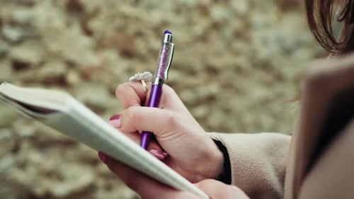 Woman Hands With A Purple Pen On The Paper Close Up