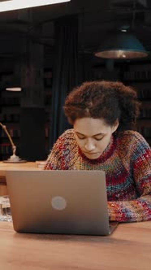 Mixed Race Female Studying Remotely Using Laptop at Modern Library