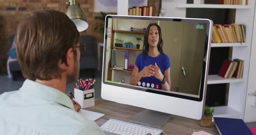 Caucasian male teacher having a video call with female colleague on computer at school