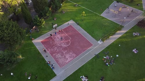 People playing on pink public basketball court immersed in green landscape, Buenos Aires in Argentin