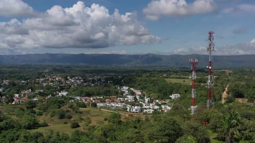 drone aerial shot of mobile technology antennas with a village behind the antennas