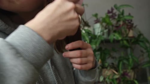 Woman Combs Hair and Inspects Hairbrush Indoors