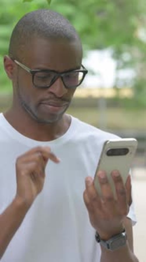 Young Man Using Mobile Phone in Green Urban Setting