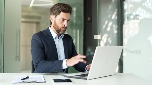 Frustrated businessman in a formal suit having problems with software or service on laptop computer