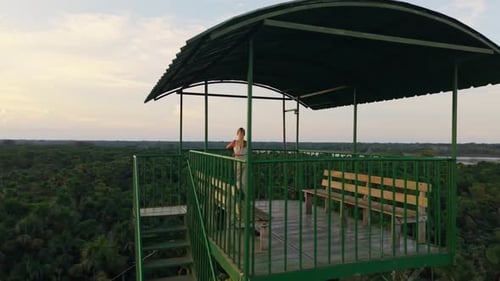 Una viajera rubia se para en lo alto de una torre de observación contemplando la verde selva amazónica durante