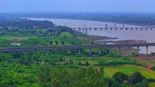 The bridge stretches over a river near the large green farmland, connecting roads and fields.