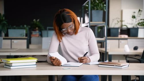 Woman Writes in Notebook in Modern Office