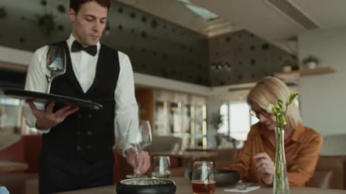 Waiter Bringing Wine Glasses on Tray Serving Diverse Female Guests in Restaurant
