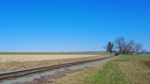 An Approaching Steam Passenger Train Blowing Smoke and Steam on a Sunny Day