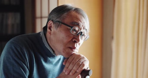 Thinking, sad and senior Asian man in home for depression, nostalgia and reflection in living room