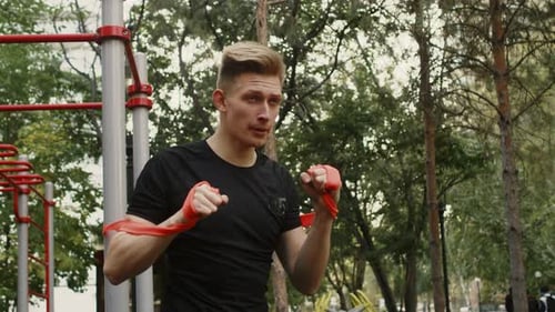 Young Man Boxing with Resistance Band Outdoors