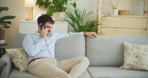 Man Relaxing on Sofa Talking on Phone Indoors