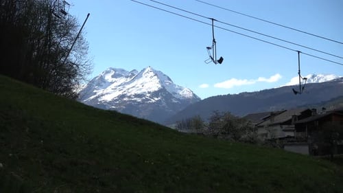 Sunny snow top mountain landscape in the French alps with ski lifts in the foreground.