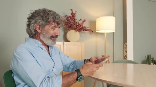 Mature Man Using Mobile Phone at Home