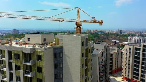 Drone shot construction crane near new residential buildings.
