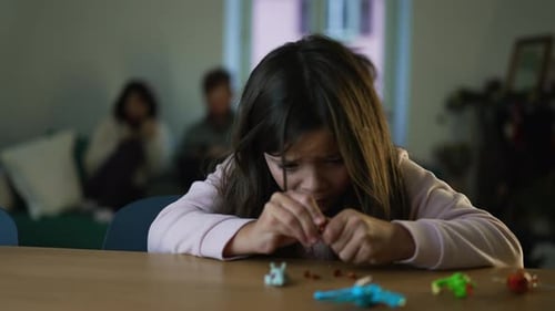 Enfant participant à l'assemblage de jouets à la maison, assis près d'une table en train de se concentrer sur le bâtiment