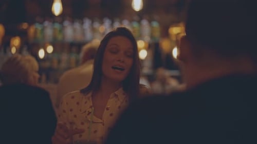 Woman smiling and holding a drink at a bar with blurred background