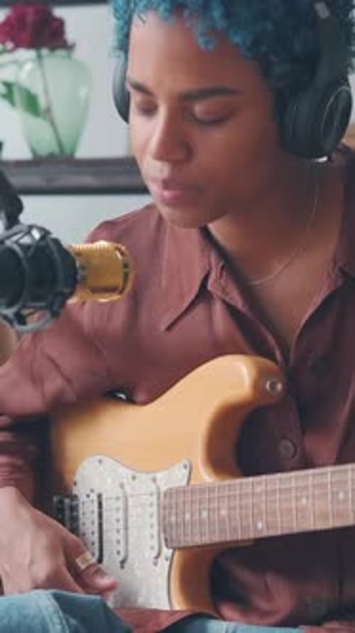 Young African American Woman Singer Plays Guitar and Sings Into Microphone