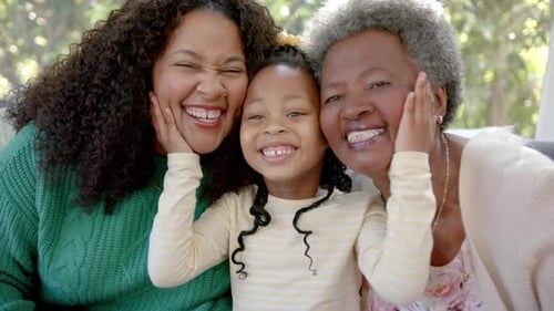 Portrait of african american mother, daughter and grandmother smiling in sunny room, slow motion