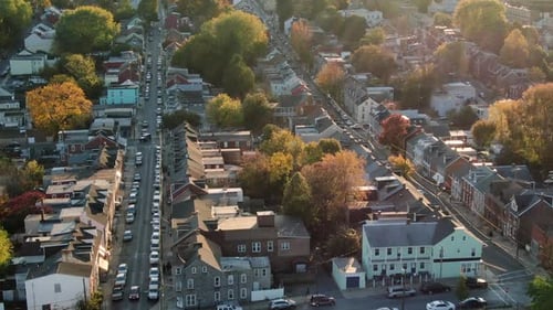 Urban America aerial dolly shot, tilt up during autumn fall sunset, houses line city streets in Lanc