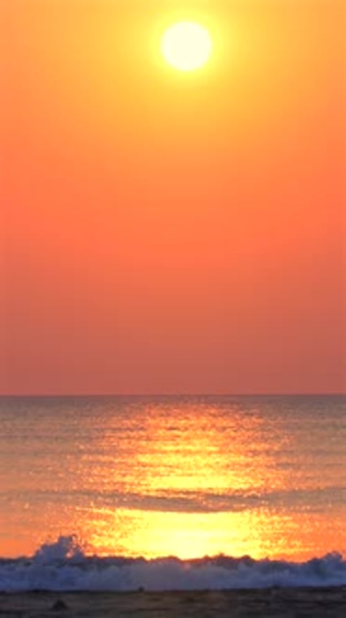 Coucher de soleil sur l'océan avec un ciel orange vif se reflétant sur l'eau calme