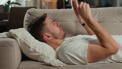 Man Relaxing on Couch Looking at Phone