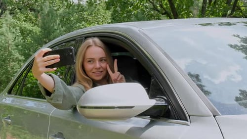 Blonde Frau hat auf der Straße ein Auto angehalten, um ein Selfie zu machen, Zeitlupe, junger Tourist, der die Gegend erkundet