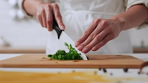 Woman Chopping Fresh Parsley in Bright Kitchen