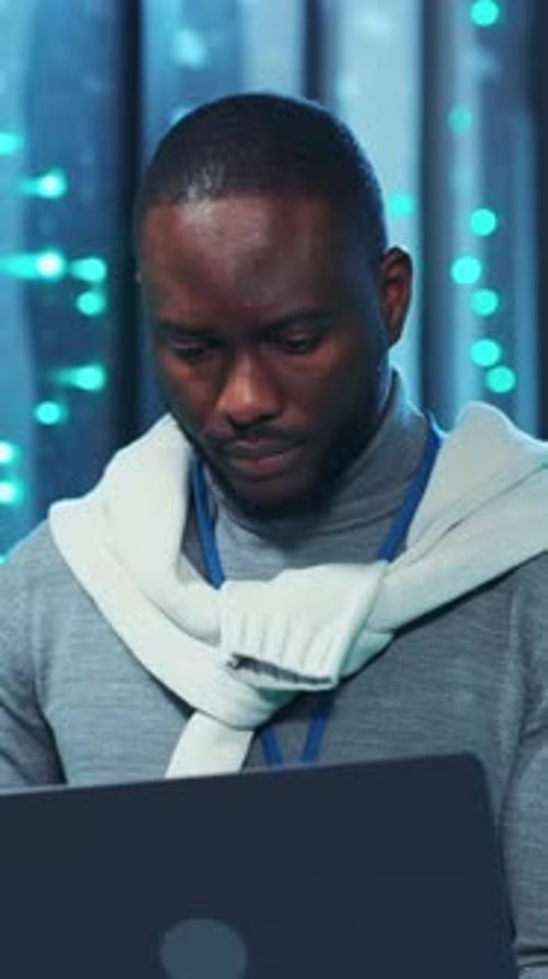 Man Working in a Server Room with Laptop