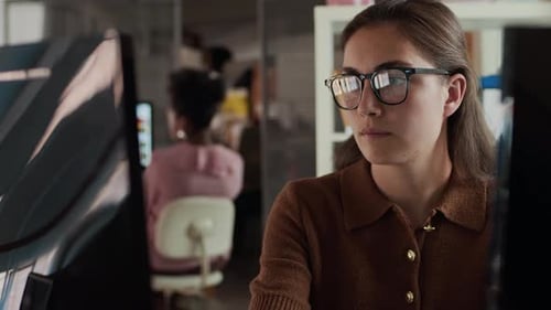 Jovem mulher escrevendo em nota adesiva durante o trabalho no computador no escritório