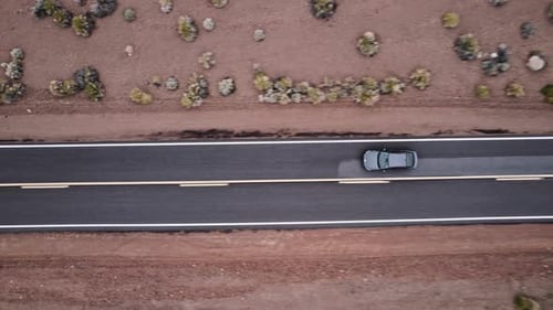 Aerial Drone Shot of a Car Driving on a Long Isolated Road in the Desert