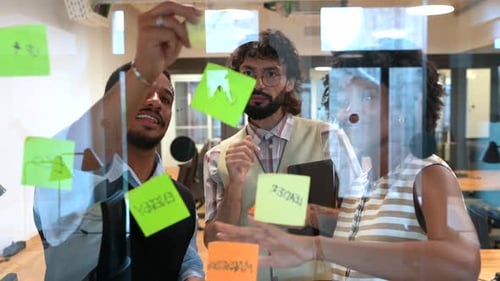Three Office Workers Brainstorming Together on Glass Board