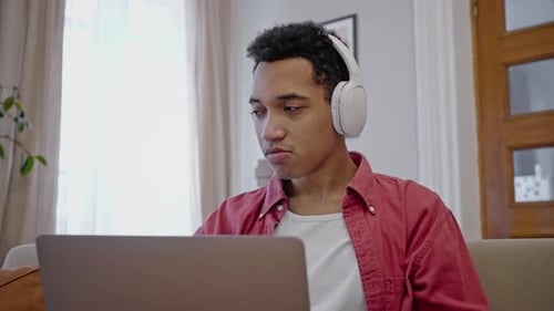 Young Adult With Headphones Using Laptop at Home
